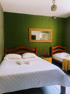 Un dormitorio con una cama blanca con una pared verde. en Pousada Portobello, en Recife