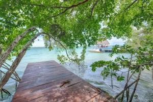a wooden bridge over a body of water with a boat at Casa Luna in Bacalar