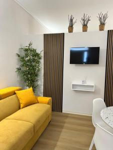 - un salon avec un canapé jaune et une télévision dans l'établissement Noto da MARE, à Noto Marina