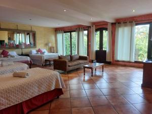 a room with two beds and a living room with a couch at Casa Mia Hotel in Antigua Guatemala
