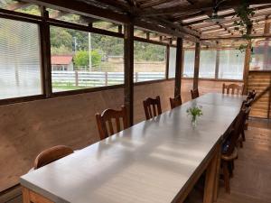 a large table and chairs in a room with windows at Haryugetu Guesthouse in NASA in Kaiyo