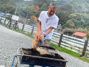 a man is cooking food on a grill at Haryugetu Guesthouse in NASA in Kaiyo