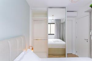 a white bedroom with a mirror and a bed at Edificio Easy Life | Mercês - Curitiba | Gonzaga Stays in Curitiba
