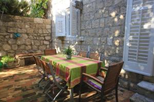 a patio with a table and chairs and a stone wall at House Korta in Cavtat