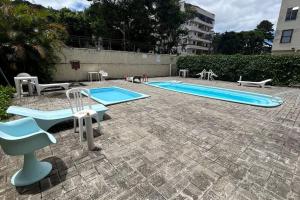 a swimming pool with two chairs and a table at Studio 330 - aconchegante, 500m da Feirinha do Alto, com Garagem e Wi-Fi 500MB in Teresópolis