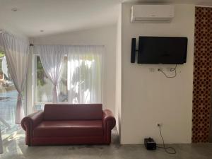 a living room with a couch and a television on a wall at Casa de la Cruz in Mariquita