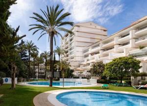 a large apartment building with a swimming pool and a palm tree at Beautiful Marbella Apartment in Marbella
