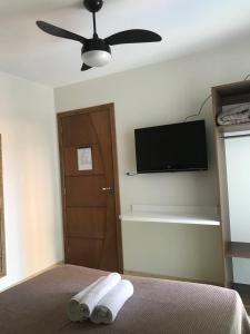 a bedroom with a ceiling fan and a bed with towels at Pousada Souza & Souza in Barra Velha