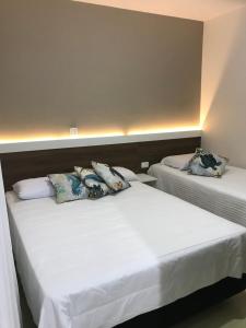 two beds in a room with white sheets and pillows at Pousada Souza & Souza in Barra Velha