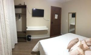 a bedroom with a bed and a flat screen tv at Pousada Souza & Souza in Barra Velha