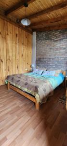 Una cama grande en una habitación con una pared de ladrillos. en Rincon del Sur, en El Bolsón