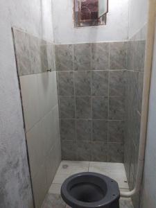 a bathroom with a toilet with a tiled wall at Kitnets in Contagem +8 photos