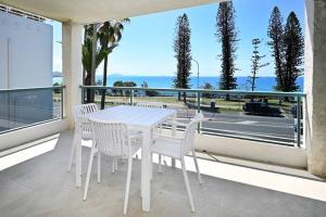 a white table and chairs on a balcony with a view of a street at Alex Heads, Prime Location, Stunning Views in Alexandra Headland