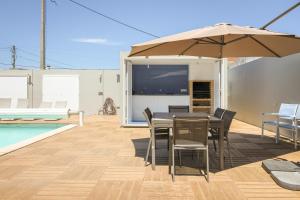 Un patio con una mesa y sillas y una sombrilla. en Dunas Villa, en São Jacinto