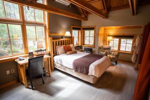 a bedroom with a bed and a desk and windows at Sleeping Lady Mountain Resort in Leavenworth +37 photos