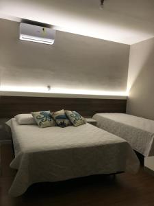 a bedroom with two beds and a light on the wall at Pousada Souza & Souza in Barra Velha