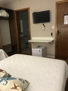 a bedroom with a bed and a flat screen tv at Pousada Souza & Souza in Barra Velha