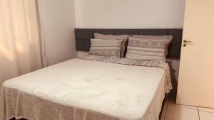 a small bedroom with a bed with white sheets and pillows at Casa grande em bairro tranquilo in Pato Branco