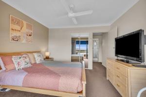 a bedroom with a bed and a flat screen tv at Hydra 8 in Merimbula