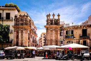 une rue avec des tables et des parasols devant les bâtiments dans l'établissement Scilia casa vacanza, à Palerme