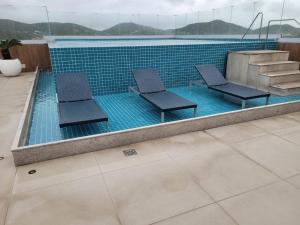 a swimming pool with two chairs and a staircase at HOTEL BOSSA NOVA 224 - Ótimo Apto com cozinha para até 03 hóspedes in Cabo Frio