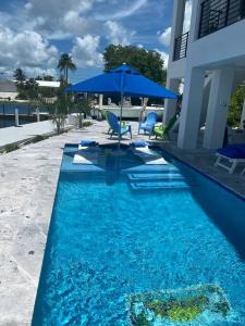 ein blauer Pool mit einem Tisch und einem Sonnenschirm in der Unterkunft Newly built home in Cudjoe Key in Cudjoe Key