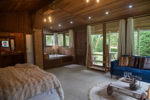 a bedroom with a blue bed and a bath tub at Pousada Irreplaceable in Visconde De Maua +55 photos