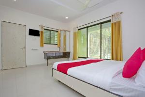 a bedroom with a bed and a desk and a window at Hotel O Capital O Sai Icon Residency in Titwala +15 photos