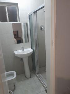 ein weißes Badezimmer mit Waschbecken und Dusche in der Unterkunft Fife Avenue Guest House in Harare