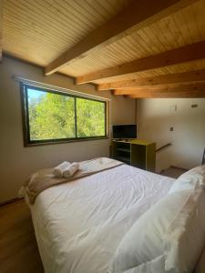 a bedroom with a large white bed with a window at Pucura Eco Lodge in Licán Ray