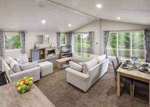 a large living room with white furniture and windows at Hamlet Lodge Retreat At Calloose Holiday Park in Hayle