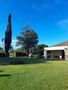 a green yard with a building and a tree at Casa Quinta Estilo Campo in Lobos