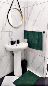 baño con lavabo, espejo y alfombra verde en Forest Green Unit 2, en Durban