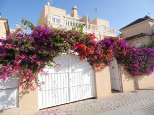 a white gate with purple and red flowers on it at Villa La Zenia, Private pool, 10min walk to La Zenia Beach, for 6 people in Playas de Orihuela