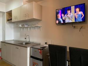 Il comprend une cuisine avec un évier et une télévision murale. dans l'établissement Netflix & Chill at Pablo's Homestay-Grace Residences Tower 4, à Manille