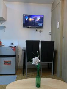 a room with two chairs and a table with a vase with a flower at Netflix & Chill at Pablo's Homestay-Grace Residences Tower 4 in Manila