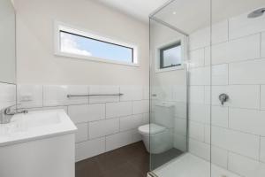 a white bathroom with a toilet and a sink at Seaside Getaway in Point Lonsdale +12 photos