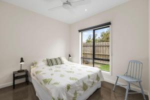 a bedroom with a bed and a chair and a window at Seaside Getaway in Point Lonsdale
