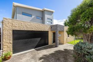 a detached house with a garage in a driveway at Seaside Getaway in Point Lonsdale