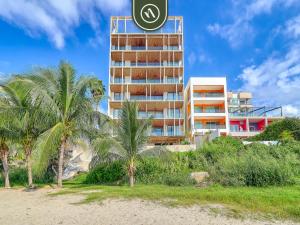 a tall building with palm trees in front of a beach at Luxury 4 BR Oceanfront Condo - Private Beach - Pool in Cruz de Huanacaxtle