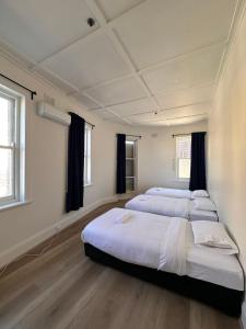 a room with three beds in it with windows at Leichhardt Centre Comfy Stay in Sydney