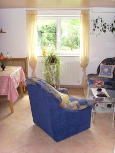 ein Wohnzimmer mit einem blauen Stuhl und einem Tisch in der Unterkunft Ferienwohnung Adelheid in Eggenbach