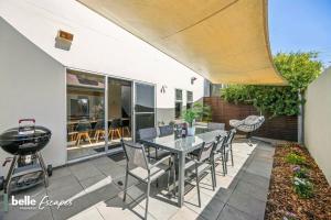 a patio with a table and chairs and a grill at 3 BR Townhouse Near Airport-City-Beach in Thebarton