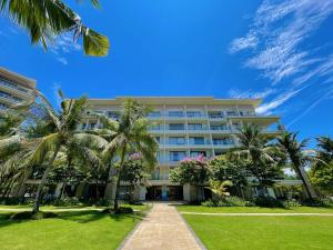a building with palm trees in front of it at Diamond Beach Villa Da Nang in Da Nang