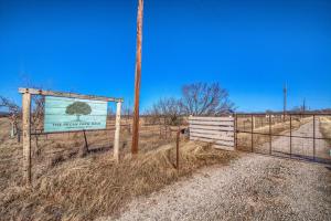 a sign in a field with a gate and a fence at Pecan Farm Haus in Fredericksburg