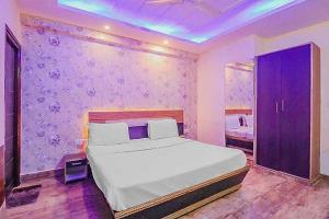 a bedroom with a white bed and a purple wall at Super Hotel O Vivaan Residency in Rohtak
