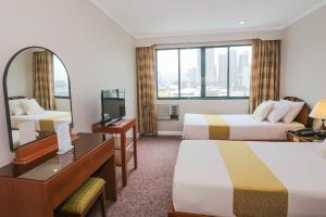 a hotel room with two beds and a desk and a mirror at Holiday Plaza Hotel - Cebu in Cebu City +31 photos