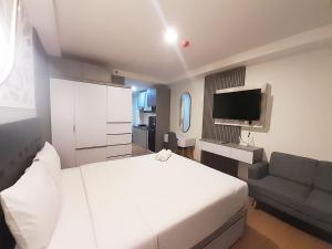 a bedroom with a white bed and a couch at Modern Classic Studio at Mataram City Apartment By Travelio in Kejayan