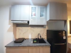 a kitchen with white cabinets and a black refrigerator at Modern Classic Studio at Mataram City Apartment By Travelio in Kejayan +6 photos