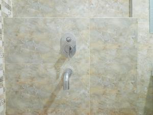 a shower with a shower head on a tiled wall at Modern Classic Studio at Mataram City Apartment By Travelio in Kejayan